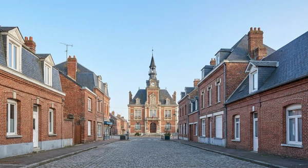 Photographie réaliste de la ville de Tergnier en Aisne montrant une perspective urbaine ou architecturale caractéristique : vue d'une rue principale, façades de bâtiments typiques de la commune, point de repère local ou paysage urbain représentatif de Tergnier en Picardie. L'image doit être une photographie authentique sans personnes au premier plan, prise de jour en conditions naturelles, représentant clairement l'identité visuelle de cette commune.