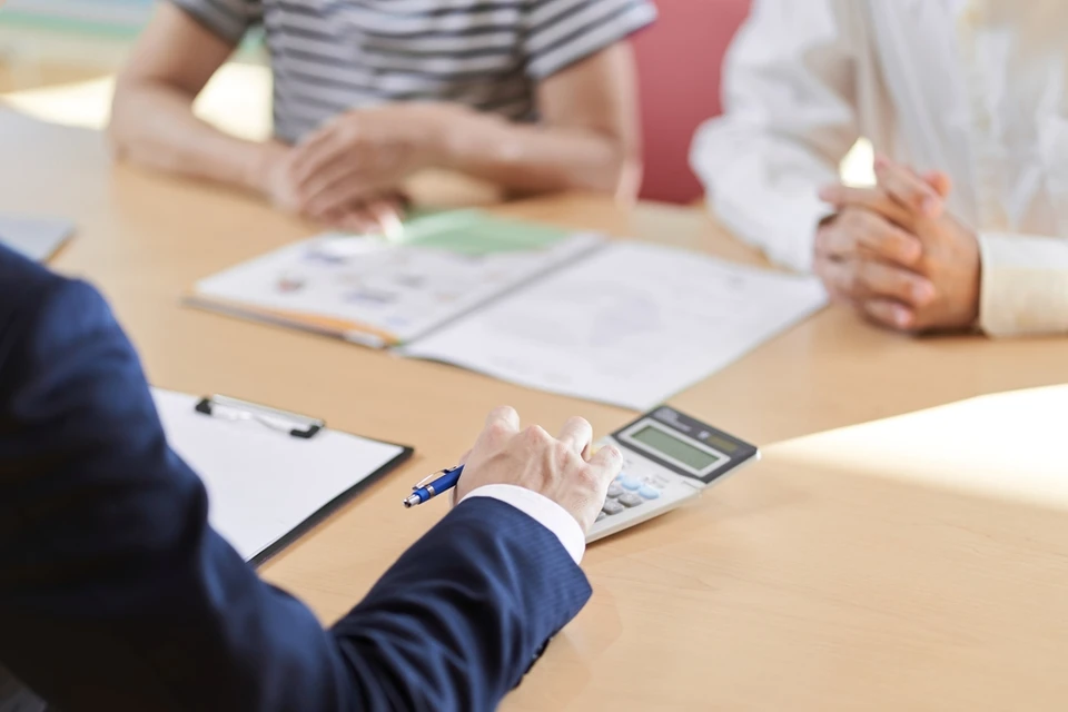 Réunion d'affaires autour d'une table en bois avec plusieurs personnes analysant des documents contractuels
